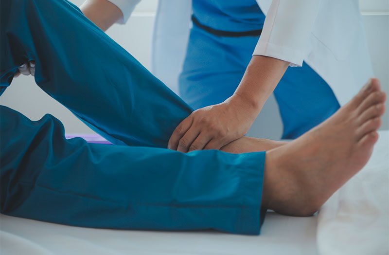 A chiropractor examining a patient's leg and ankle during a treatment session - Chiropractor Brunswick GA A chiropractor examining a patient's leg and ankle during a treatment session - Chiropractor Brunswick GA
