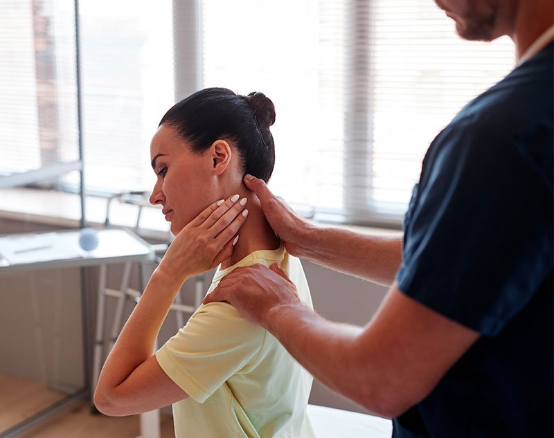 A chiropractor assessing a patient's neck and shoulder as she holds her neck, indicating discomfort - Chiropractor Brunswick GA A chiropractor assessing a patient's neck and shoulder as she holds her neck, indicating discomfort - Chiropractor Brunswick GA