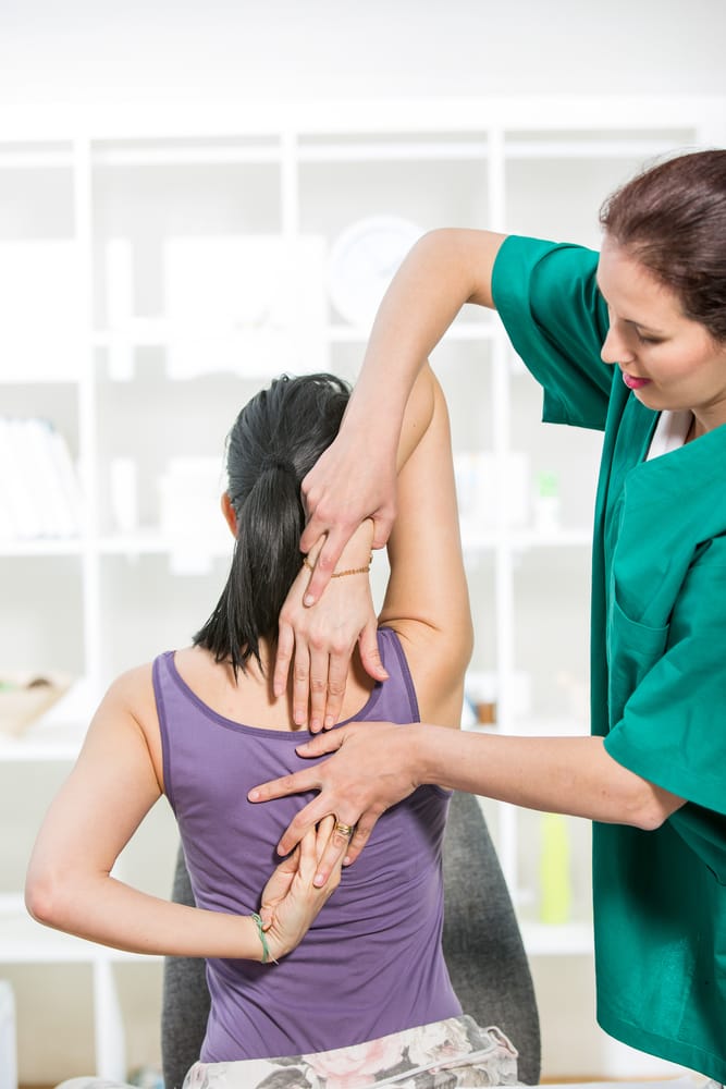 A chiropractor performing a spinal adjustment on a patient lying face down on a treatment table - Chiropractor Brunswick GA