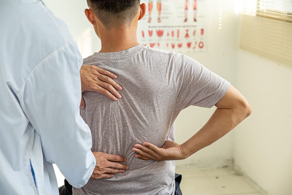 A healthcare professional performs a hands-on lower back and spinal evaluation to identify pain sources and support personalized treatment planning – Pain Management Brunswick GA